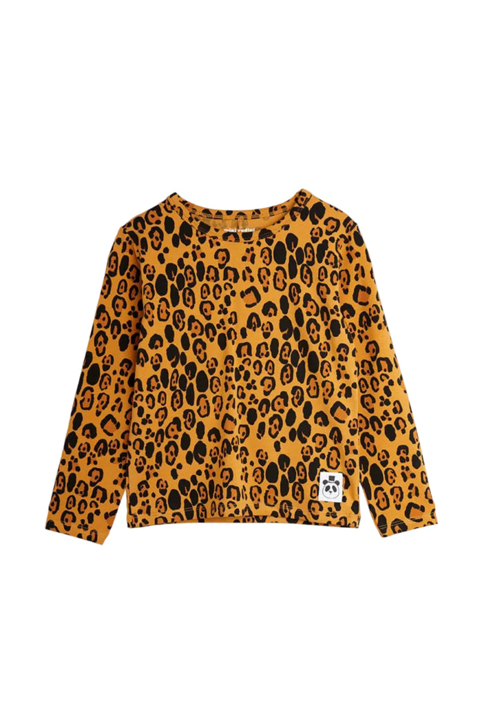 A long-sleeve crewneck top featuring an all-over leopard print pattern in mustard yellow and black, with a small white brand patch on the lower right hem.