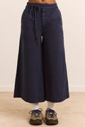 Navy blue wide-leg pants with a tie waist worn by a person on a beige background