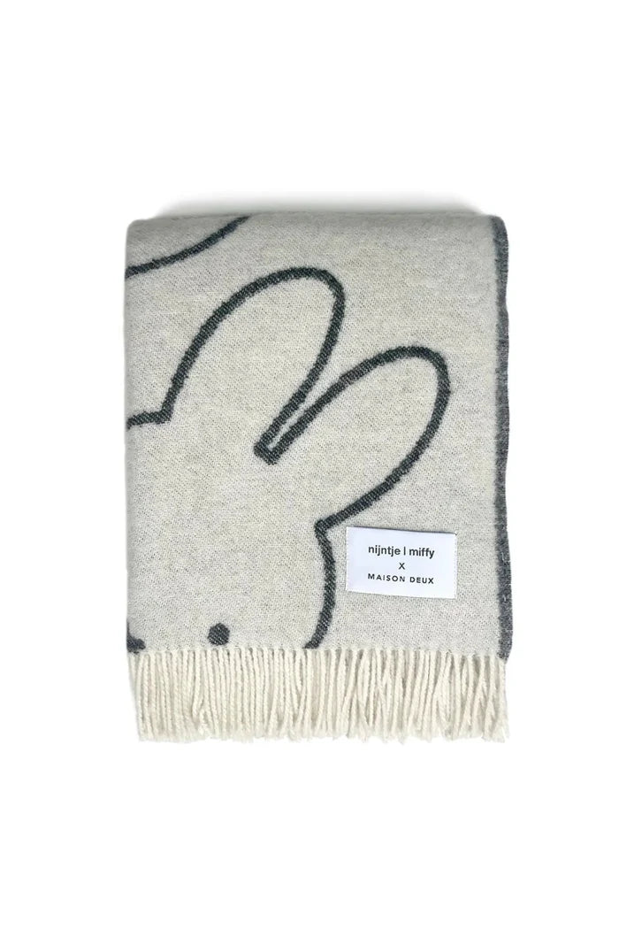 Gray blanket with black bunny design and brand label on a white background