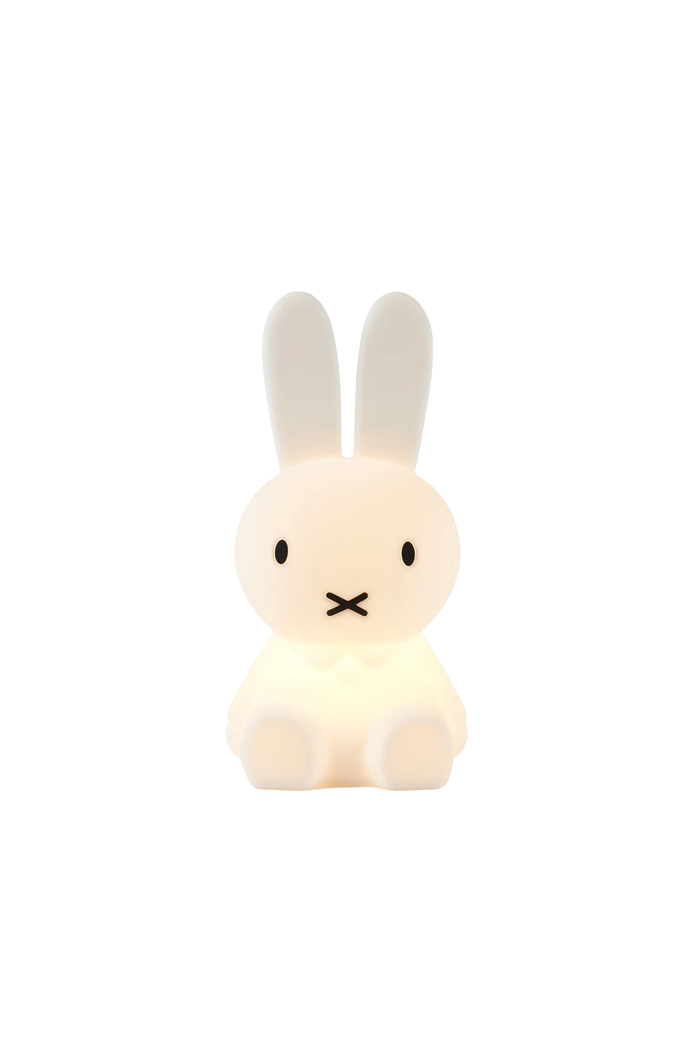 A Miffy-style bunny-shaped night light glowing with a warm white light, centered on a solid white background.