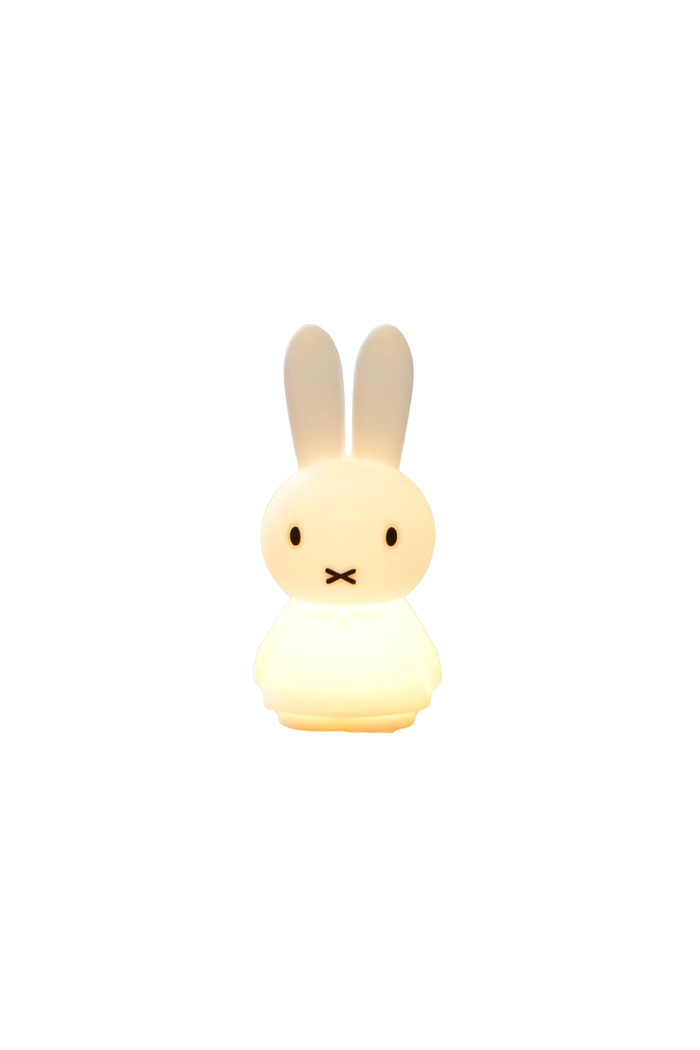 A small rabbit-shaped night light glowing with a warm yellow light, featuring long upright ears, simple black eyes, and a stitched mouth on a plain white background.