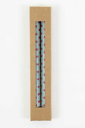 Two light blue tapered candles with red polka dots in cardboard box