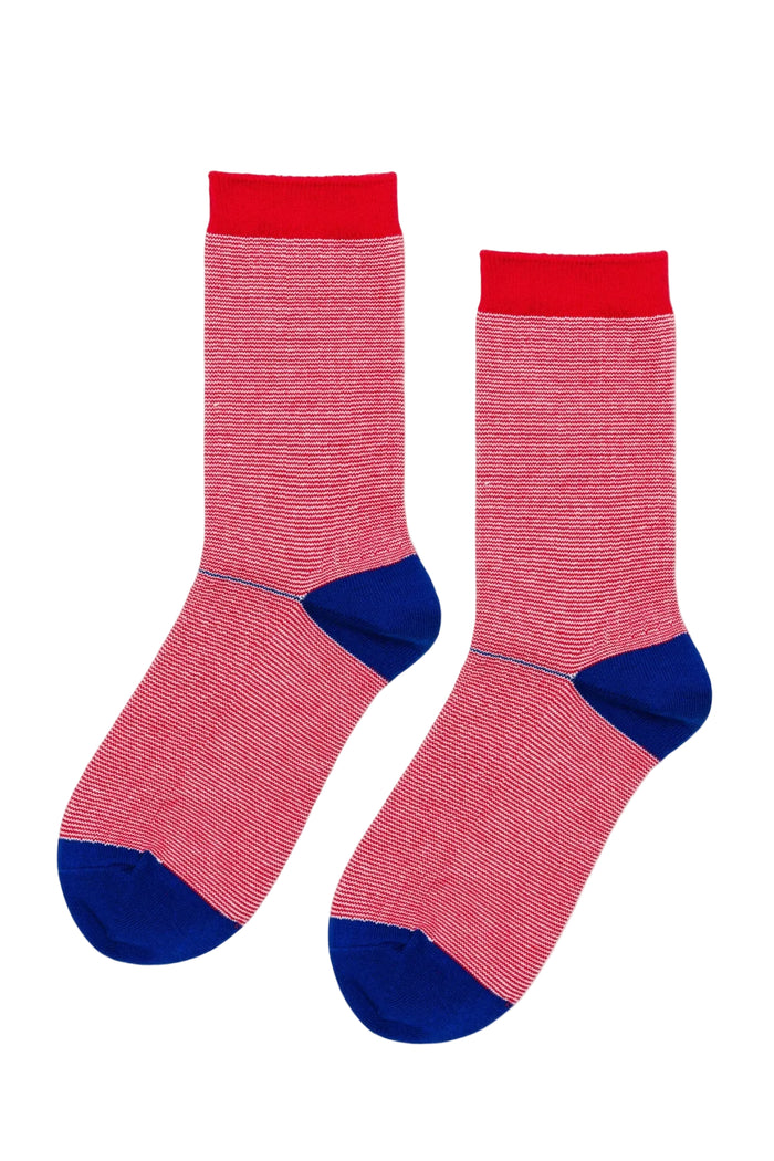 A pair of red socks with a fine white stripe and contrasting blue heel and toe on a white background.