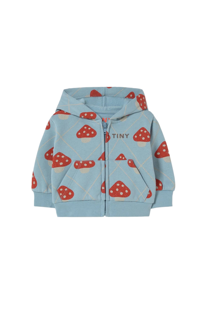 A light blue zip-up hoodie for babies, featuring an all-over print of red and white mushrooms, with the brand name 'TINY' printed on the chest, displayed against a solid off-white background.