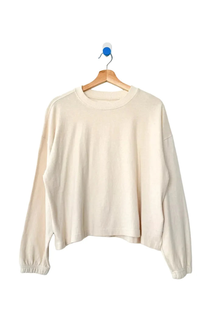 Beige sweater on a wooden hanger against a white background