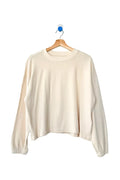 Beige sweater on a wooden hanger against a white background