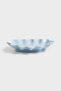 Light blue ceramic bowl with wavy edge on a white background