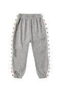 A pair of kids' heather gray sweatpants with white side stripes featuring a repeating pattern of small red stars, shown against a plain white background.