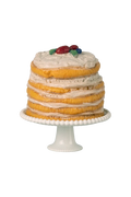 Mini layered cake with white frosting and fruit on top, placed on a white cake stand.