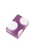 A purple bar soap with three white polka dots on a white background.