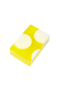 A rectangular translucent yellow soap bar with two large white circular sections, photographed on a plain white background.