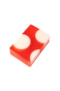A rectangular translucent red soap bar with three large off-white circular inclusions, photographed on a clean white background.