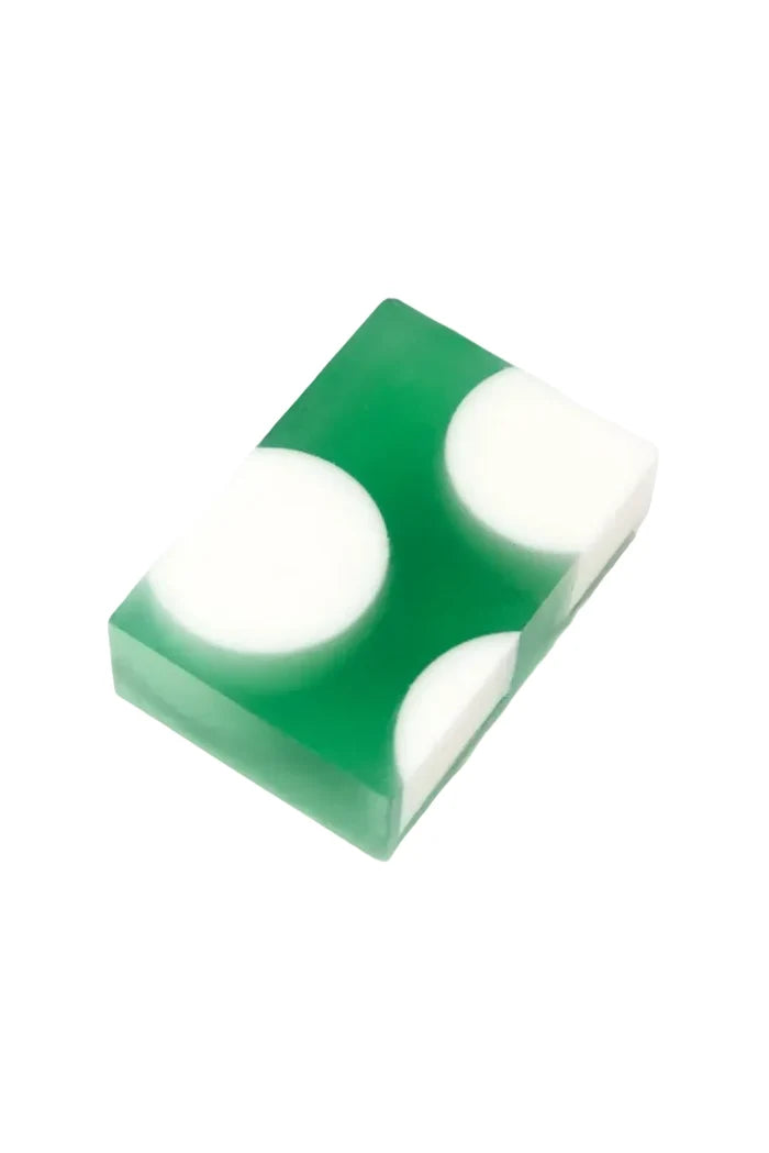 A rectangular green soap bar with three large white circular inclusions, photographed on a clean white background.