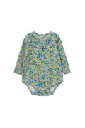 A baby long-sleeve bodysuit with a dense blue, yellow, and green floral pattern, featuring a ruffled collar, laid flat on a light cream background.