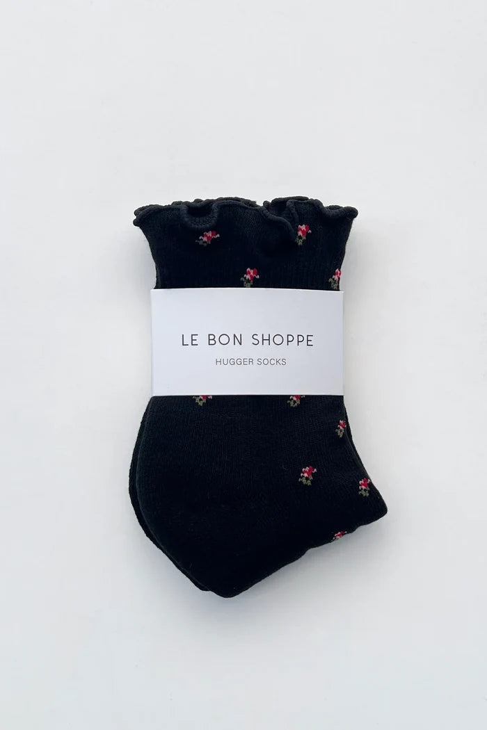 Pair of black socks with ruffles edge and flower print on white background