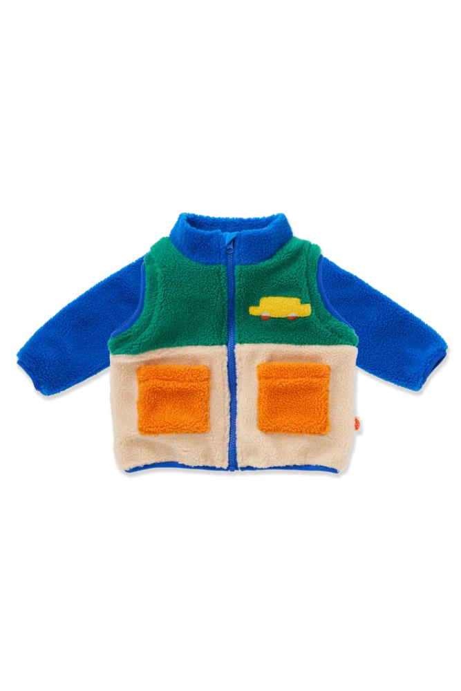 A baby sherpa zip-up vest with a color-blocked design featuring blue sleeves and collar, a green upper chest, a cream lower body, and two orange front pockets. A small yellow car patch is on the left chest.