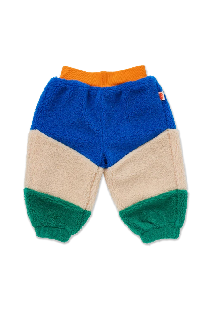 A pair of children's sherpa jogger pants in a color-blocked design with blue, beige, green, and orange sections, shown flat on a white background.