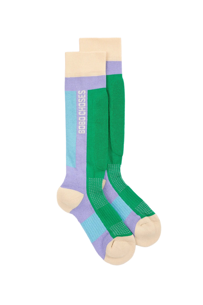 A pair of knee-high athletic socks with a color-blocked pattern of green, light blue, lavender purple, and beige.