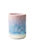 A ceramic cup with a dripping glaze design, featuring a pink and blue marbled pattern on the upper body and a solid cream-colored base, set against a plain white background.