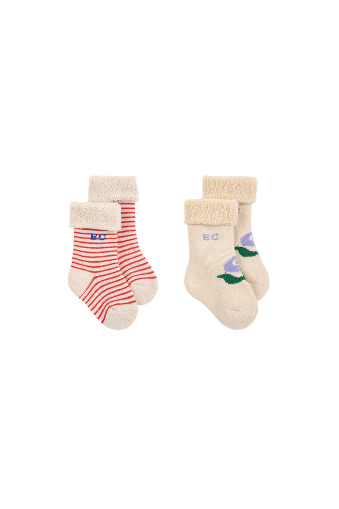 Two pairs of children's socks on a white background. The left pair has red and white horizontal stripes with a beige cuff and toe, featuring the letters 'BD' in blue.