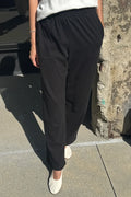 Woman wearing black sweatpants and white t-shirt standing on the sidewalk
