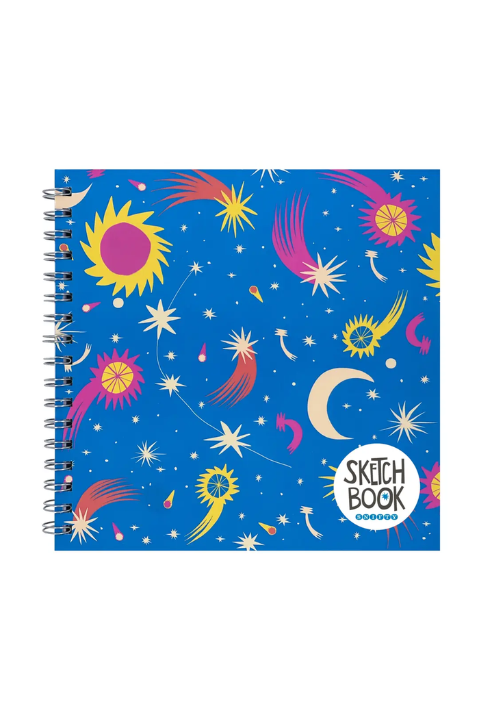 A spiral-bound sketch book with a vibrant blue cover decorated with colorful celestial illustrations, including stars, moons, and suns, with a white circular logo in the bottom right corner.