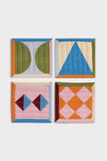 Four graphic, colorful, quilted coasters on a white background