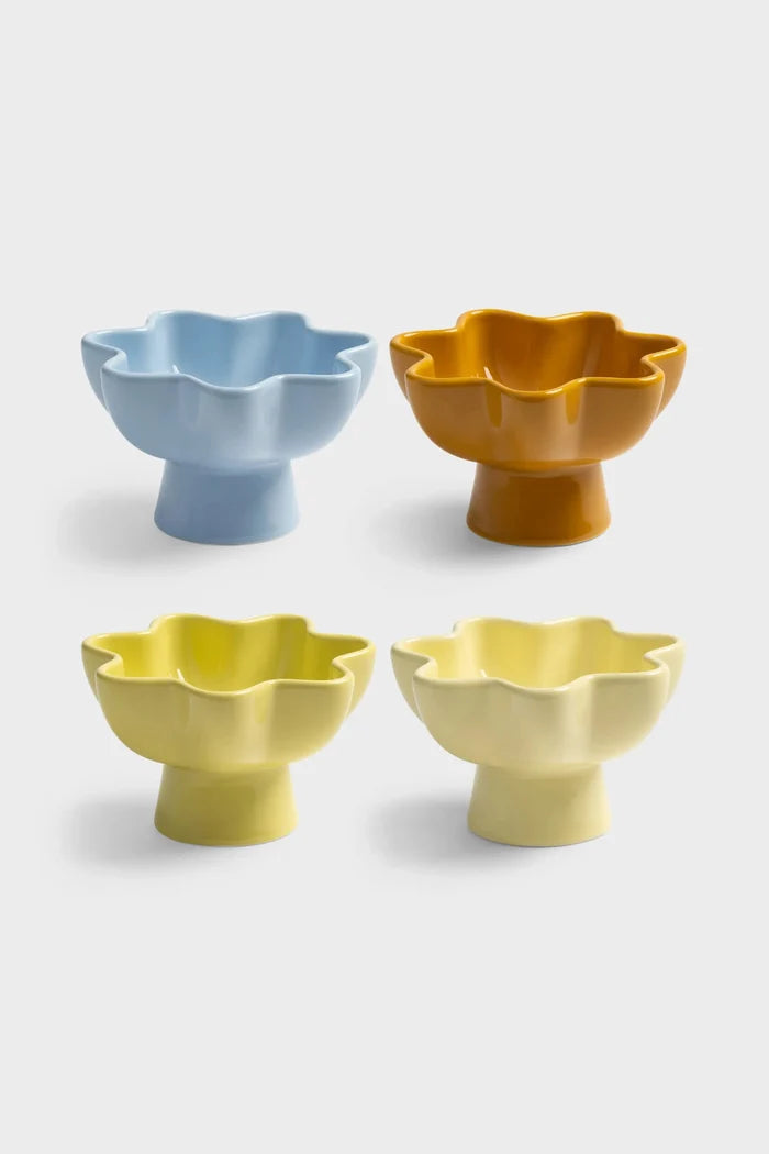 Set of four ceramic bowls with tall feet and wavy rims on a white background. One bowl is light blue, one is orange, one is chartreuse, and one yellow.