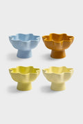 Set of four ceramic bowls with tall feet and wavy rims on a white background. One bowl is light blue, one is orange, one is chartreuse, and one yellow.