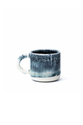 A small ceramic mug with a textured, dark blue and gray glaze that fades to a white base, shown on a plain white background.