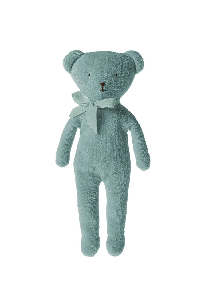 Light blue teddy bear with a white bow tie against a striped background