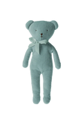 Light blue teddy bear with a white bow tie against a striped background