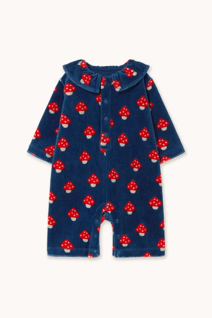 A baby long-sleeve romper in navy blue corduroy fabric, featuring an all-over red and white mushroom print, displayed flat against a light cream background.