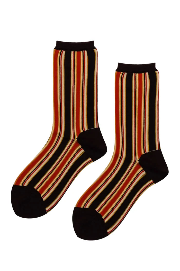A pair of crew socks with a vertical stripe pattern in black, rust orange, and cream, featuring solid black heels, toes, and cuffs, displayed against a plain white background.