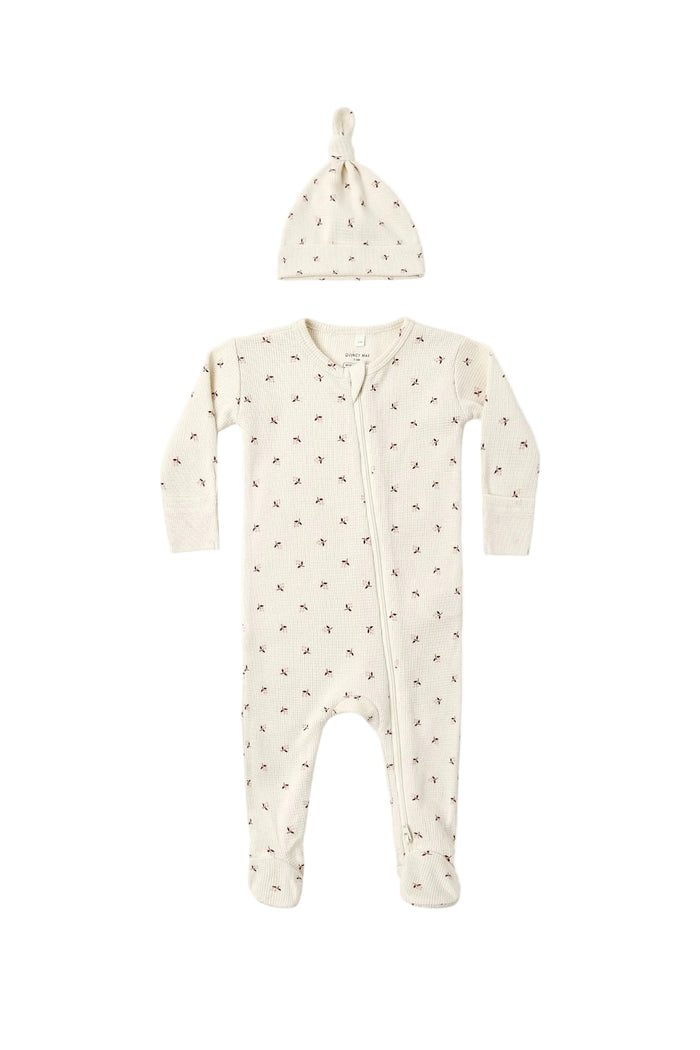 A baby sleep suit and matching knotted beanie hat in a warm cream color with a small brown daisy print, displayed flat against a solid white background.