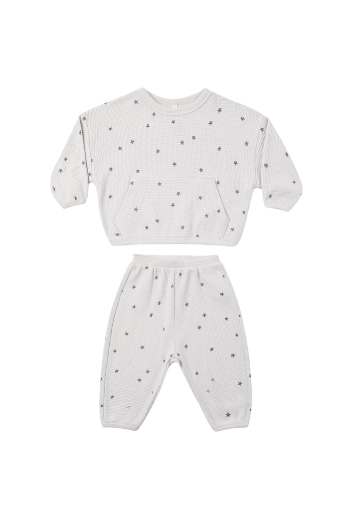A two-piece baby loungewear set consisting of a long-sleeve sweatshirt and matching pants in white, both covered in a small dark gray star pattern.