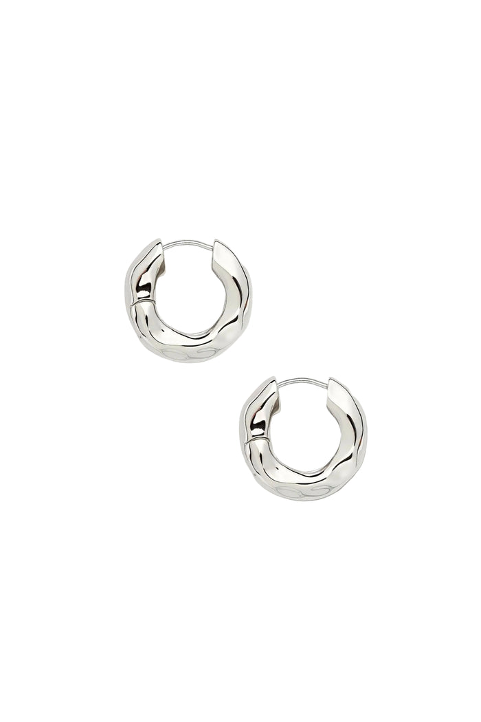 A pair of silver, wavy chunky hoop earrings on a white background.