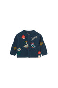 A navy blue long-sleeve cardigan for toddlers, featuring colorful embroidered motifs including a goose, mushrooms, a duck, and a bird, with the brand name 'tiny' embroidered on the chest.
