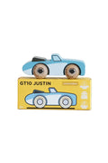 A light blue and white wooden toy race car with natural wood wheels sits on top of its yellow 'GT10 Justin Limited Edition' storage box. The box features a graphic of the toy car and age suitability markings of 2+.