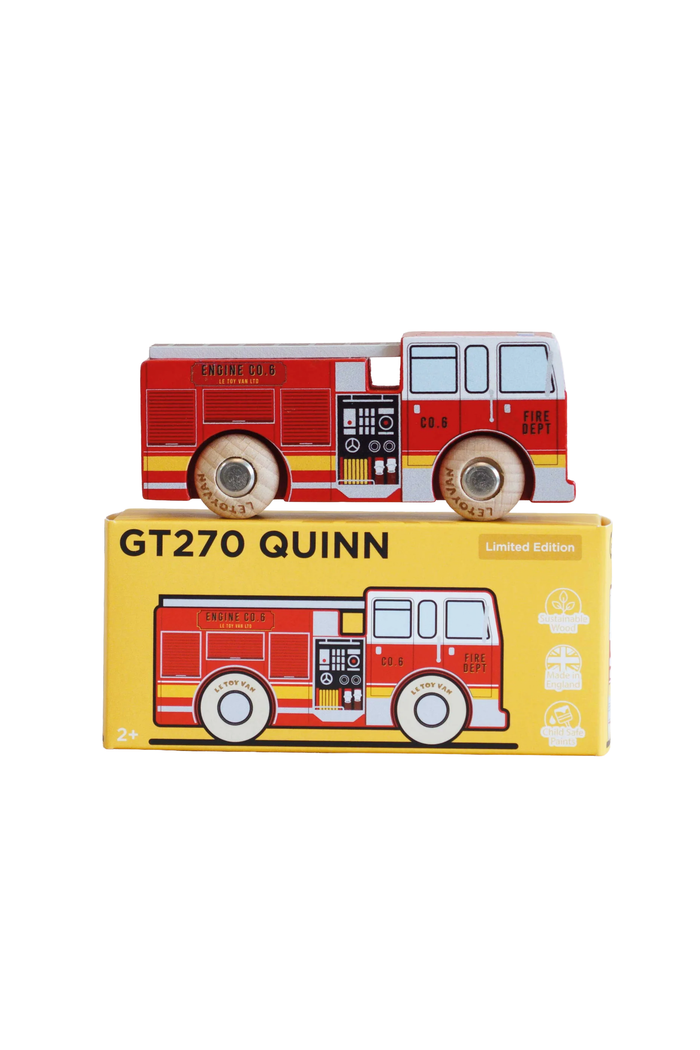 A red and white wooden toy fire truck with printed details, displayed on top of its yellow retail box labeled 'GT270 QUINN Limited Edition'.