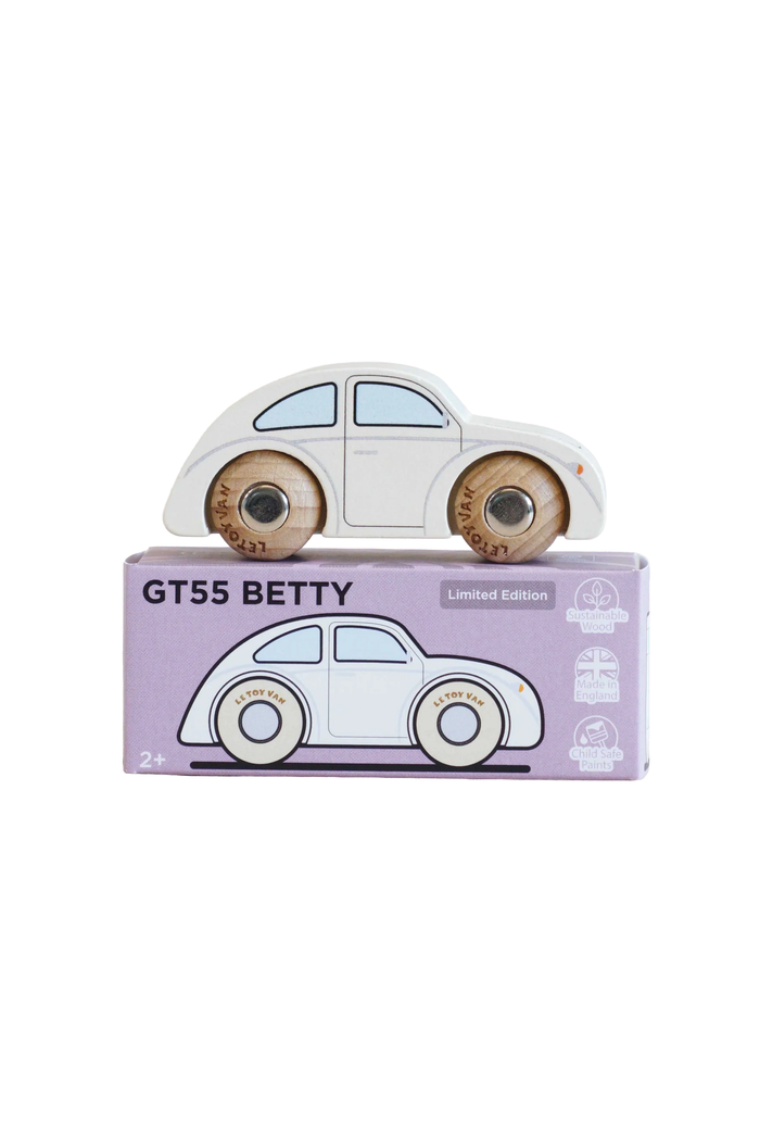 A wooden toy car shaped like a classic Volkswagen GT55 Beetle, shown resting on top of its lavender packaging box against a solid white background.