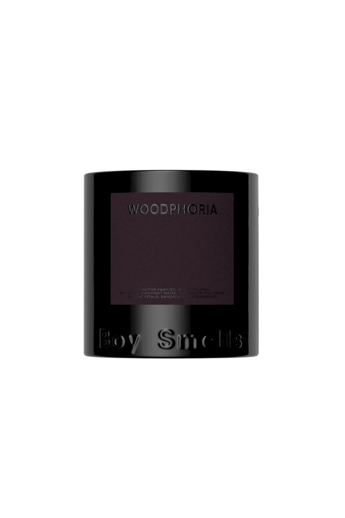 A black candle with a label reading 'Woodphoria' on the front and 'Boy Smells' on the bottom. The candle is unlit and displayed against a white background.